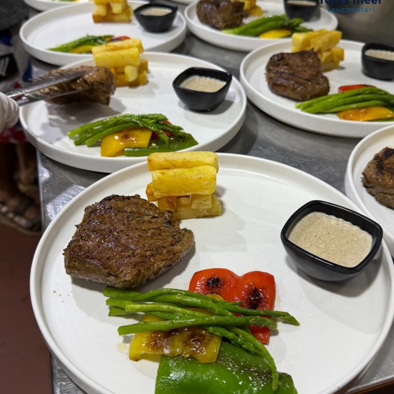 Rindersteak mit Beilagen: grünes Gemüse, Paprika, frittierten Kartoffeln und Soße.