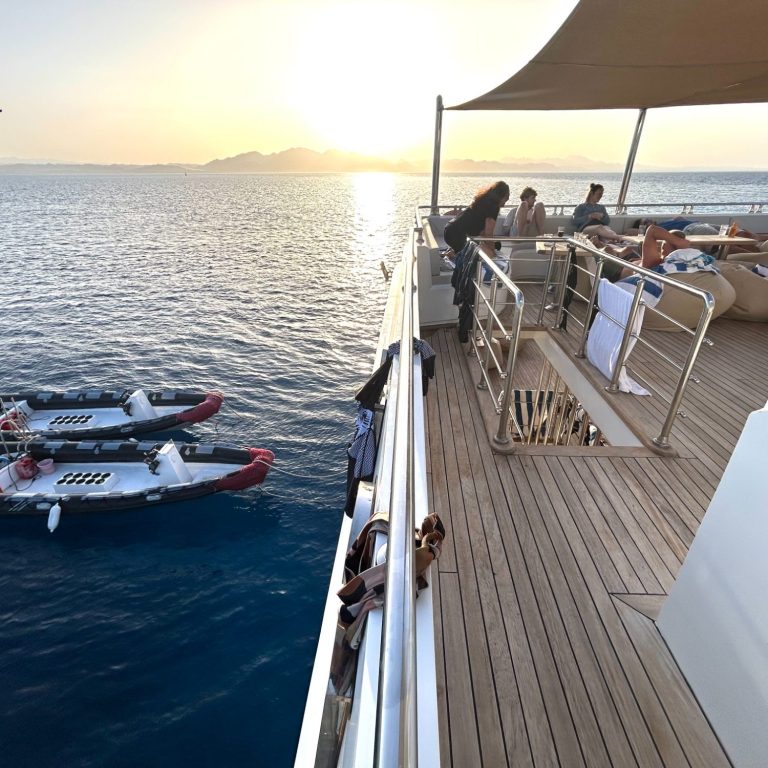 Personen entspannen auf einem Boot bei Sonnenuntergang über dem Wasser.