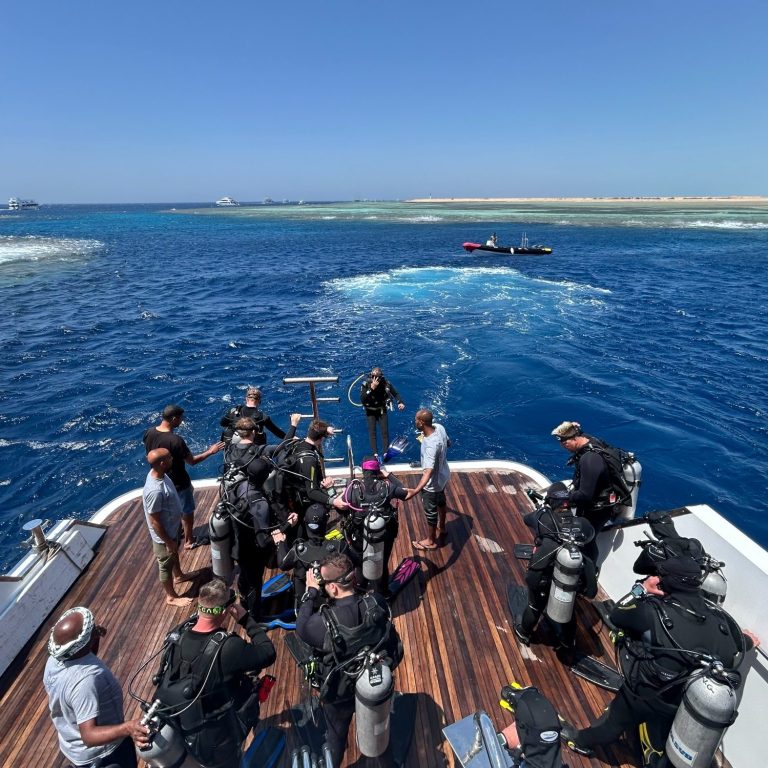 Taucher und Crew auf einem Boot, bereit zum Abtauchen in klaren Gewässern.